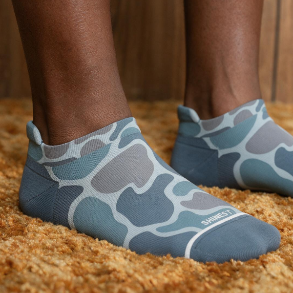 Gray duck-camo ankle socks on shag carpet, the Shinesty name stitched across each heel tab