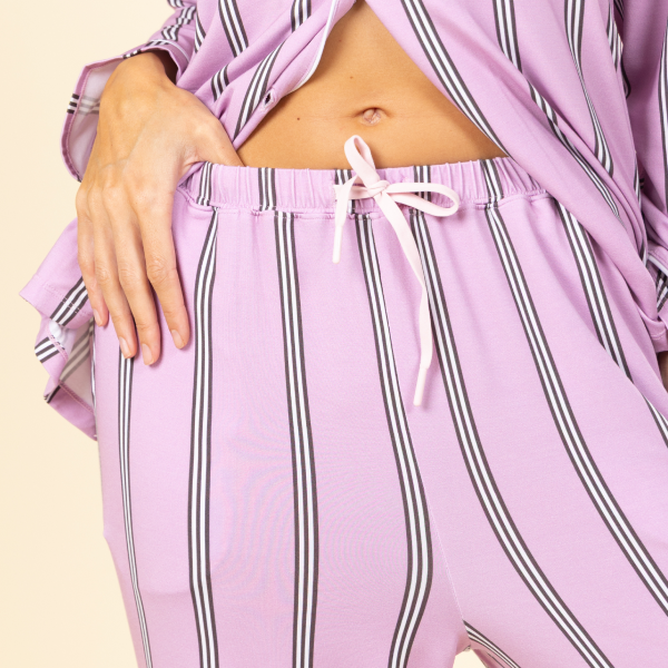 Lavender striped pajama pants with a drawcord waist and matching piped top, midriff in view
