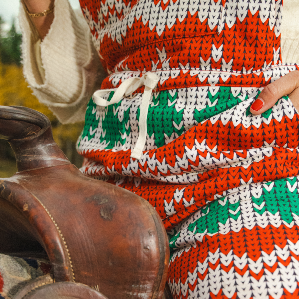 Hand tucked into the side pocket of red and green Shinesty pajamaralls, drawstring waist beside a saddle
